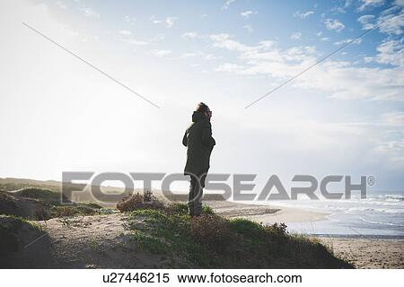 Stock Photography - "Silhouetted man on windy dunes looking out to sea, Sorso, Sassari, Sardinia, Italy". Fotosearch