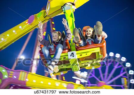 Sister and brother mid air on fairground ride at night View Large Photo Image Stock Photo - Sister and brother mid air on fairground ride at night. Fotosearch