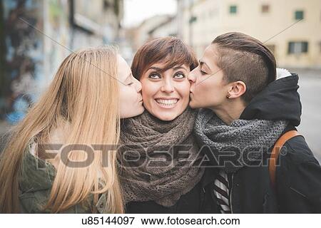 Sisters kissing woman on street View Large Photo Image Stock Photo - Sisters kissing woman on street. Fotosearch