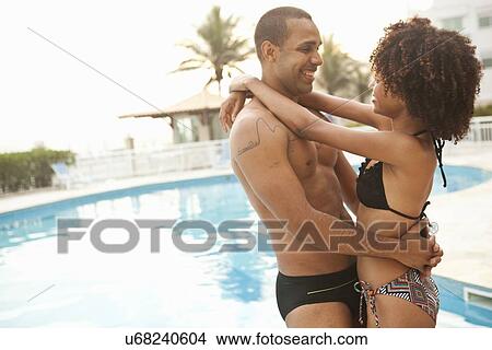 Picture - "Smiling couple hugging at hotel poolside, Rio De Janeiro, Brazil". Fotosearch
