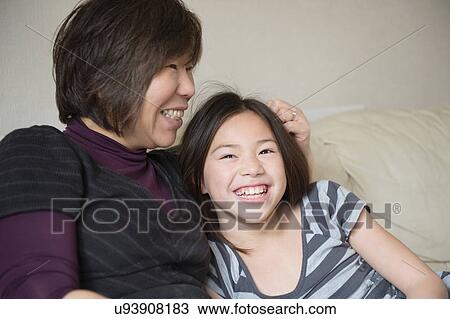 Smiling girl and her mother sitting on sofa View Large Photo Image Stock Image - Smiling girl and her mother sitting on sofa. Fotosearch