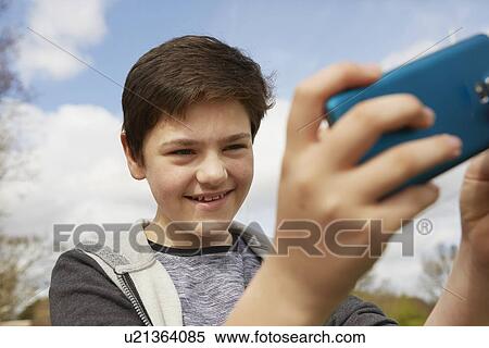 Smiling teenage boy taking smartphone selfie View Large Photo Image Stock Photography - Smiling teenage boy taking smartphone selfie. Fotosearch