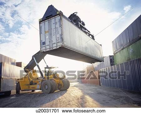Stock Image - "Stacker lifting shipping container in port, Grimsby, England, United Kingdom". Fotosearch