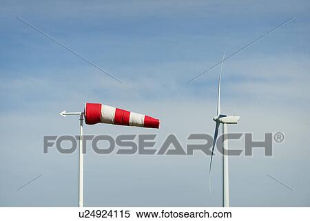 Stock Photography - "Striped wind sock and wind turbine against blue sky, Netherlands". Fotosearch