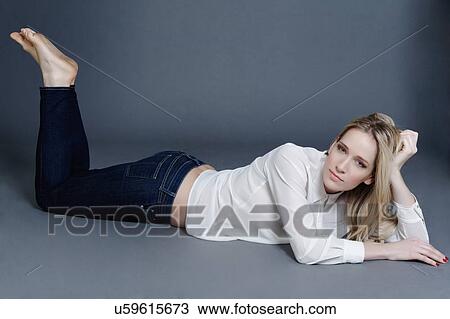 Stock Image - Studio portrait of a blond mid adult woman laying down smiling at camera. Fotosearch