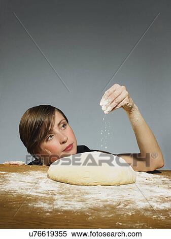 Studio portrait of young woman sprinkling flour on bread dough View Large Photo Image Stock Photography - Studio portrait of young woman sprinkling flour on bread dough. Fotosearch