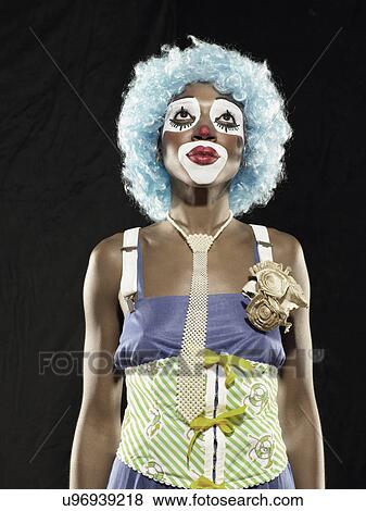 Studio portrait of young woman wearing clown face paint and blue wig looking up View Large Photo Image Stock Photo - Studio portrait of young woman wearing clown face paint and blue wig looking up. Fotosearch