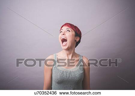 Stock Photograph - Studio portrait of young woman with short pink hair shouting. Fotosearch