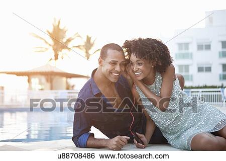 "Stylish couple sharing earphones at poolside, Rio De Janeiro, Brazil" View Large Photo Image Stock Photograph - "Stylish couple sharing earphones at poolside, Rio De Janeiro, Brazil". Fotosearch