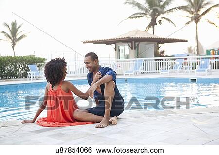 Stock Photograph - "Stylish couple sitting at hotel poolside, Rio De Janeiro, Brazil". Fotosearch