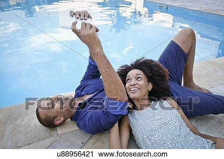 "Stylish couple taking digital tablet selfie on poolside, Rio De Janeiro, Brazil" View Large Photo Image Stock Image - "Stylish couple taking digital tablet selfie on poolside, Rio De Janeiro, Brazil". Fotosearch