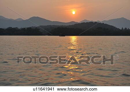 "Sunset over lake, mountains in distance, Hangzhou, China" View Large Photo Image Stock Image - "Sunset over lake, mountains in distance, Hangzhou, China". Fotosearch