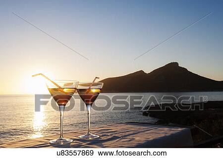 Stock Photo - "Sunset over sea with two cocktails on table, Mallorca, Spain". Fotosearch