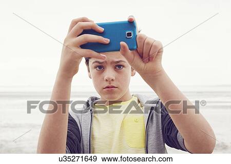 "Teenage boy taking smartphone selfie at seaside, Southend on Sea, Essex, UK" View Large Photo Image Stock Photo - "Teenage boy taking smartphone selfie at seaside, Southend on Sea, Essex, UK". Fotosearch