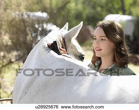 Stock Photograph - Teenage girl grooming grey horse. Fotosearch