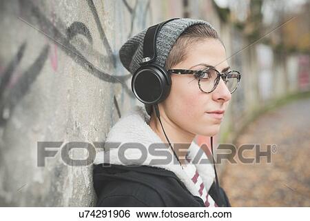 Stock Photograph - Teenager with headphones by graffiti wall. Fotosearch