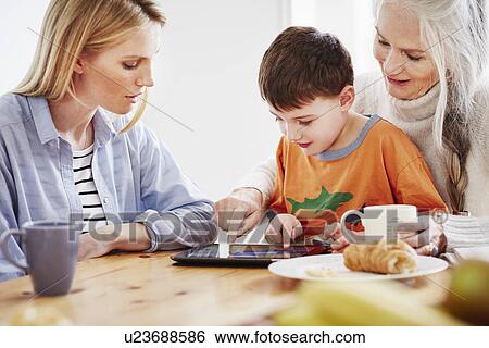 Three generation family using digital tablet View Large Photo Image Stock Photograph - Three generation family using digital tablet. Fotosearch