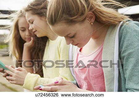 Three girls reading smartphone text messages View Large Photo Image Stock Photograph - Three girls reading smartphone text messages. Fotosearch