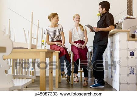 Stock Image - Three people planning work in cafe. Fotosearch
