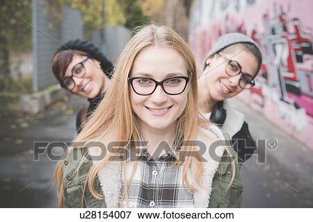 Stock Photo - "Three sisters on street, graffiti wall in background". Fotosearch