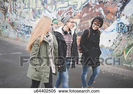 Stock Photography - Three sisters walking by graffiti wall. Fotosearch