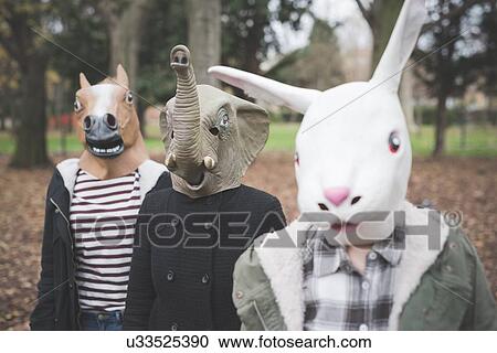 Stock Image - Three sisters wearing animal masks posing in park. Fotosearch