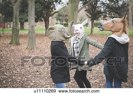 Stock Photo - Three sisters wearing animal masks dancing in park. Fotosearch