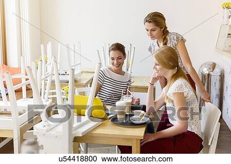 Stock Image - Three women using laptop in cafe. Fotosearch