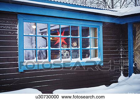 Stock Image - Two brothers looking out of snow covered cabin window at Christmas. Fotosearch
