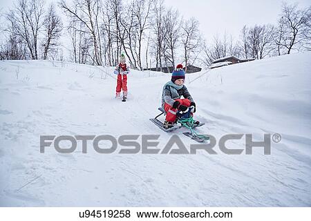 "Two brothers on toboggan and snow scooter on snow covered hill, Hemavan, Sweden" View Large Photo Image Stock Photo - "Two brothers on toboggan and snow scooter on snow covered hill, Hemavan, Sweden". Fotosearch