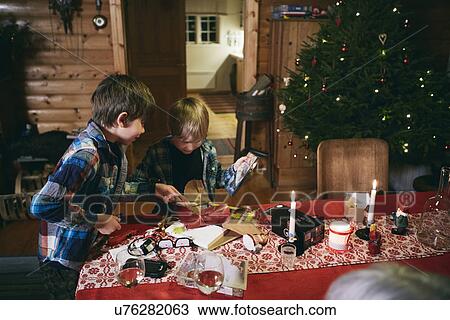 Two brothers opening Christmas presents at table View Large Photo Image Stock Image - Two brothers opening Christmas presents at table. Fotosearch
