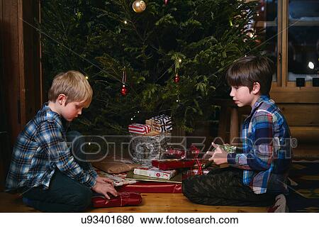 Stock Image - Two brothers opening Christmas presents. Fotosearch