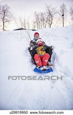 "Two brothers playing on toboggan on snow covered hill, Hemavan, Sweden" View Large Photo Image Stock Image - "Two brothers playing on toboggan on snow covered hill, Hemavan, Sweden". Fotosearch