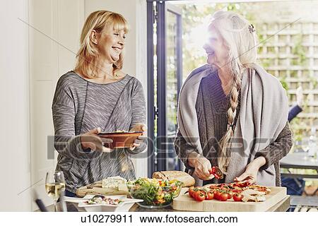 Two female friends preparing foo in kitchen View Large Photo Image Stock Image - Two female friends preparing foo in kitchen. Fotosearch