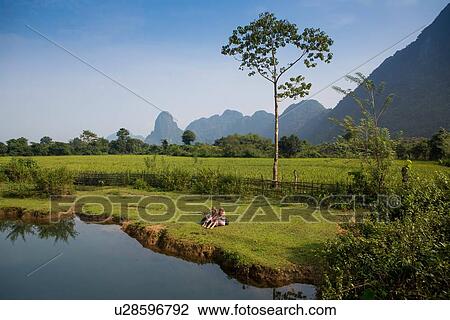 "Two female friends relaxing on Nam Song riverbank, Vang Vieng, Laos" View Large Photo Image Stock Image - "Two female friends relaxing on Nam Song riverbank, Vang Vieng, Laos". Fotosearch
