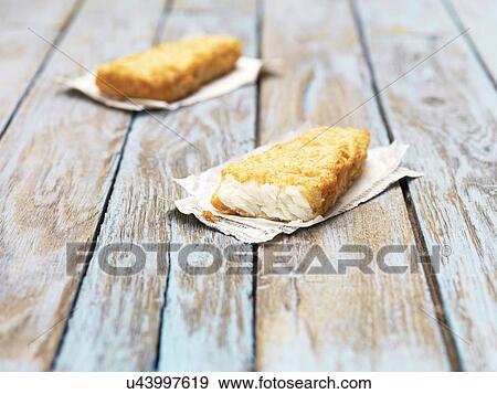 Two fried chunky battered haddock pieces on wooden table View Large Photo Image Stock Photo - Two fried chunky battered haddock pieces on wooden table. Fotosearch