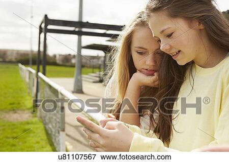 Two girls reading smartphone text message View Large Photo Image Stock Photo - Two girls reading smartphone text message. Fotosearch
