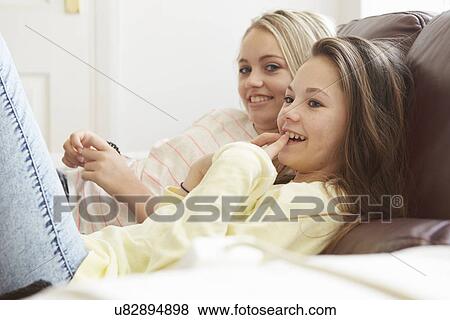Two girls watching tv from sofa View Large Photo Image Stock Photo - Two girls watching tv from sofa. Fotosearch