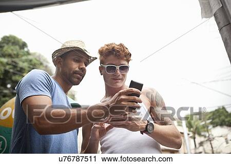 "Two male friends looking at smartphone, low angle view" View Large Photo Image Stock Image - "Two male friends looking at smartphone, low angle view". Fotosearch