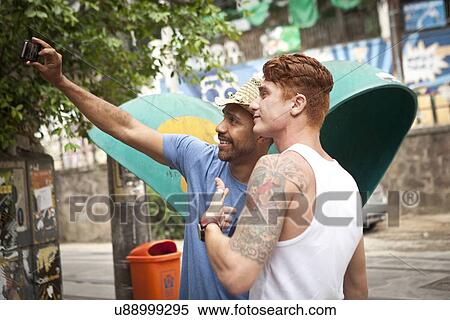 Two male friends taking self portrait together using smartphone View Large Photo Image Stock Photography - Two male friends taking self portrait together using smartphone. Fotosearch