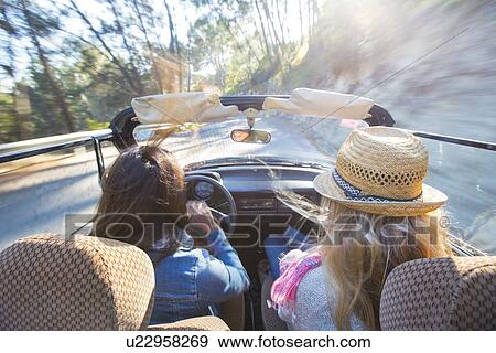 Stock Photo - "Two mature women in convertible car, rear view". Fotosearch