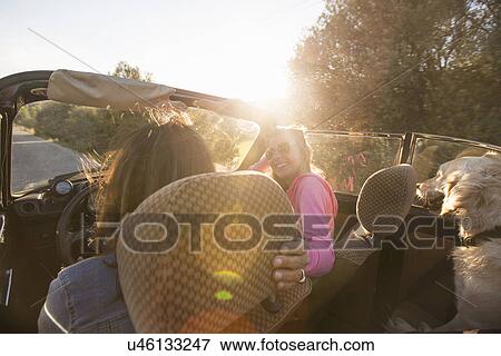Stock Photo - "Two mature women in convertible car, rear view". Fotosearch