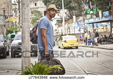 "Two men, carrying travel bags, looking for taxi" View Large Photo Image Stock Photo - "Two men, carrying travel bags, looking for taxi". Fotosearch