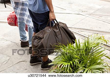 Picture - "Two men, carrying travel bags, low section". Fotosearch