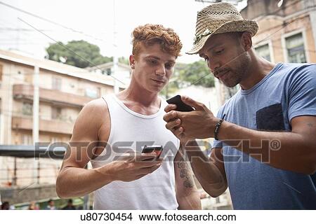 Two men looking at smartphones View Large Photo Image Picture - Two men looking at smartphones. Fotosearch