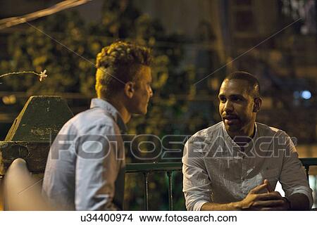 "Two men sitting at table at bar, talking" View Large Photo Image Picture - "Two men sitting at table at bar, talking". Fotosearch