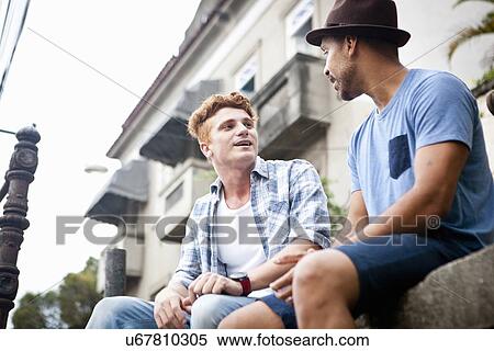 "Two men sitting on wall, talking, low angle view" View Large Photo Image Stock Photography - "Two men sitting on wall, talking, low angle view". Fotosearch