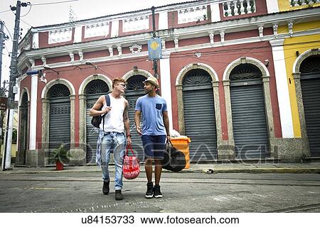 "Two men walking together, carrying travel bags" View Large Photo Image Stock Image - "Two men walking together, carrying travel bags". Fotosearch