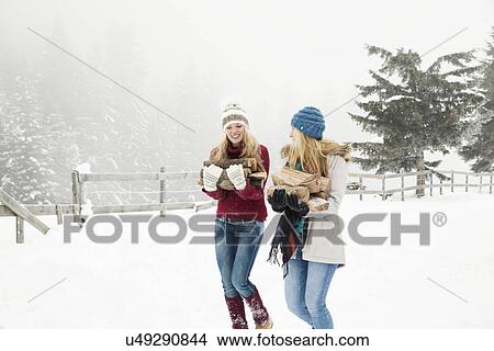 Two young female friends carrying logs in snow View Large Photo Image Picture - Two young female friends carrying logs in snow. Fotosearch