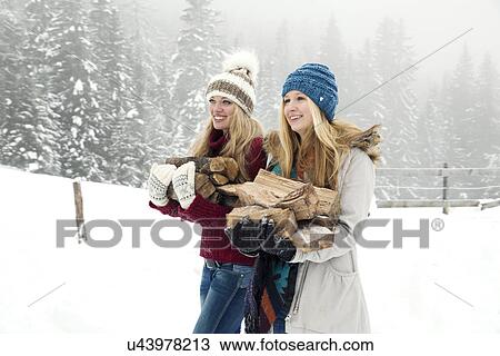 Two young female friends carrying logs in snowy mist View Large Photo Image Stock Image - Two young female friends carrying logs in snowy mist. Fotosearch